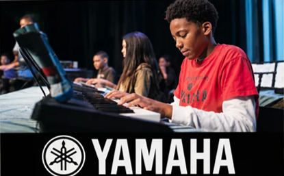 A student playing a Yamaha digital piano during a school performance, with the Yamaha logo below