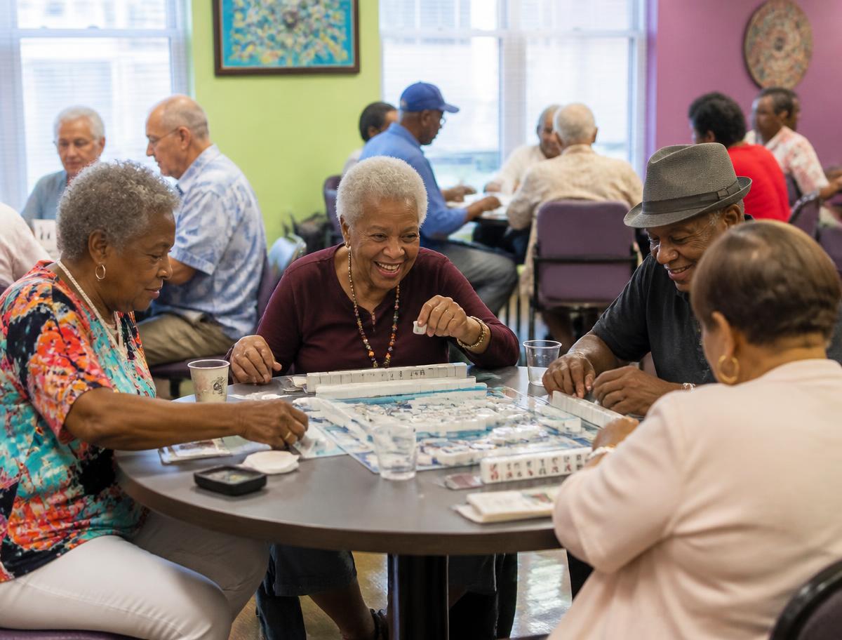 Senior center members playing mahjong and cards at round tables