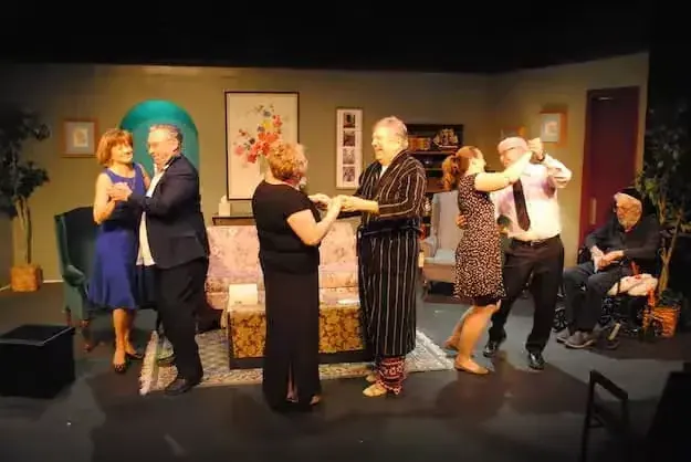 Older adults performing and dancing on stage in a community theater production