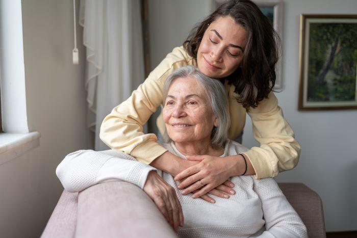 An adult daughter embracing her older mother at home