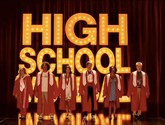 Student performers in red graduation gowns on a High School Musical stage, sharing their talents with the community