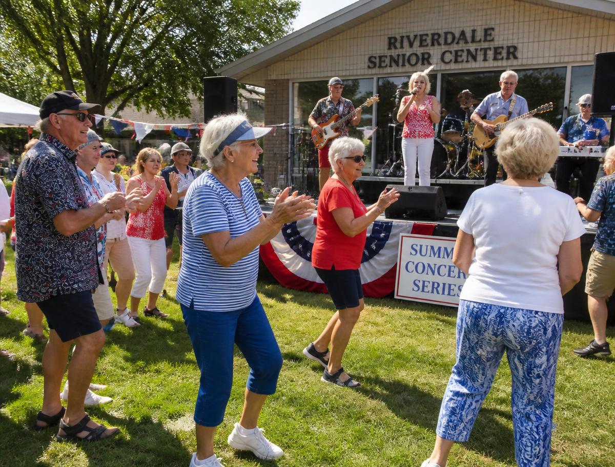 Older adults clapping and dancing at an outdoor senior center summer concert