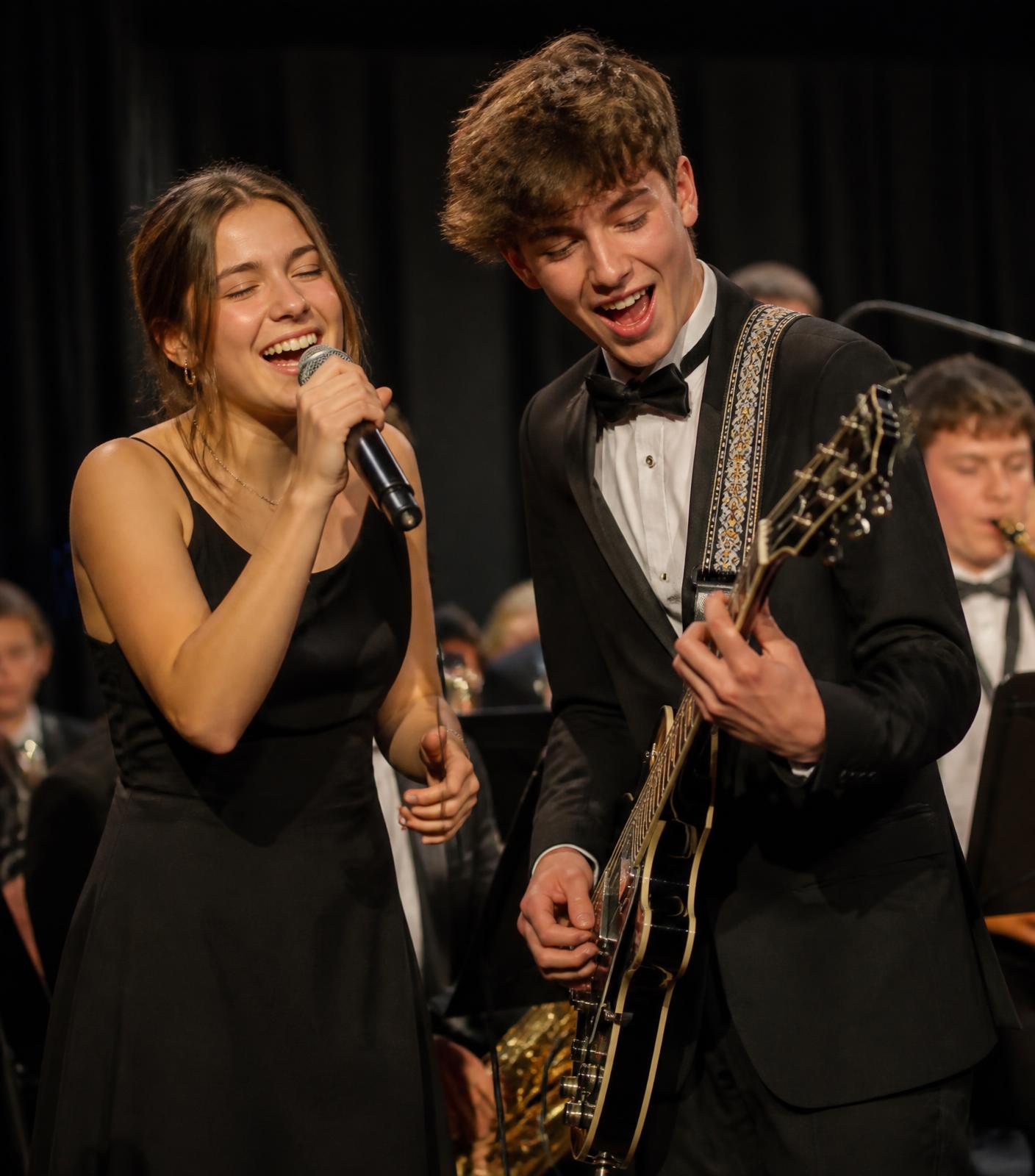 High school students singing and playing guitar together during a live performance